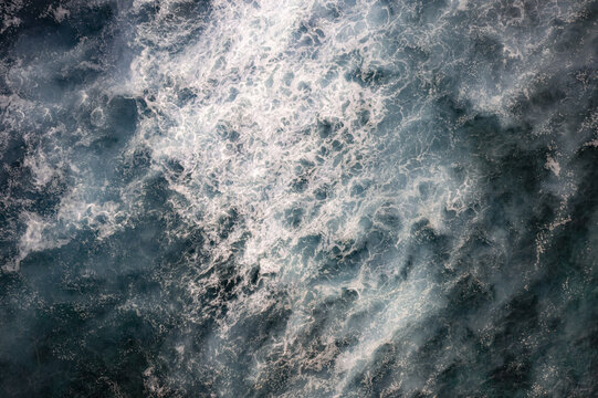 Aerial view of the churning ocean waves with white sea foam and deep blue water near the coast of Palmilla, Baja California Sur, Mexico.