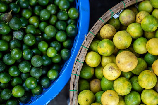 Street food market selling various kinds of citruses, baskets filled with fresh ripe green and yellow limes on sale, raw lime fruits selling at bazaar, organic exotic produce offered from farmers.