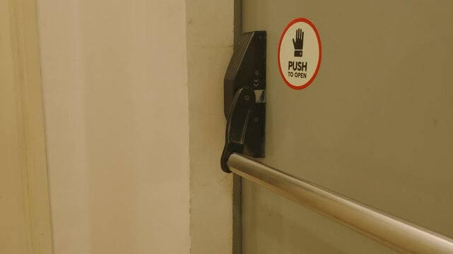 Emergency exit door with push bar and sign in a building.