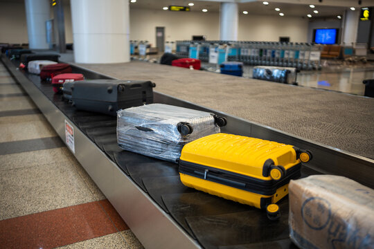 Many personal luggage transporting from airplane to arrival area in airport terminal, suitcases and bags lying on conveyor belt line, arrival zone with automatic carousel for passengers baggage. 