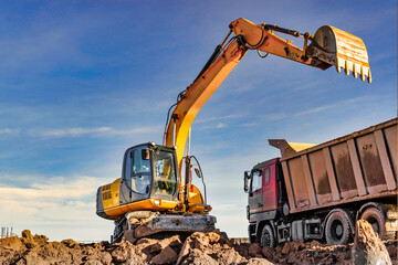 Excavator Loading Dump Truck with Soil at Construction Site © William