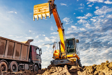 Excavator Loading Soil into Dump Truck at Construction Site © William