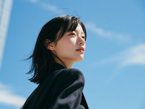 澄み切った青空を仰ぎ、深呼吸をして前向きな表情を浮かべる女性社員