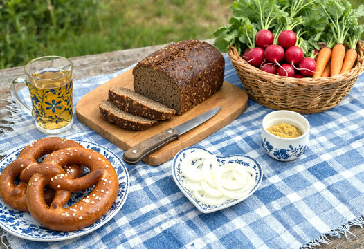Fresh outdoor picnic scene with pretzels bread radishes carrots and a rustic wooden table setting