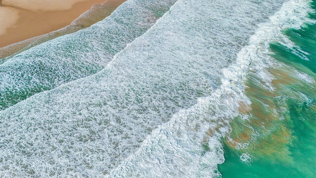 Drone aerial of emerald beach waves and shore, symbolizing seaside holidays, summer freedom, and travel inspiration.