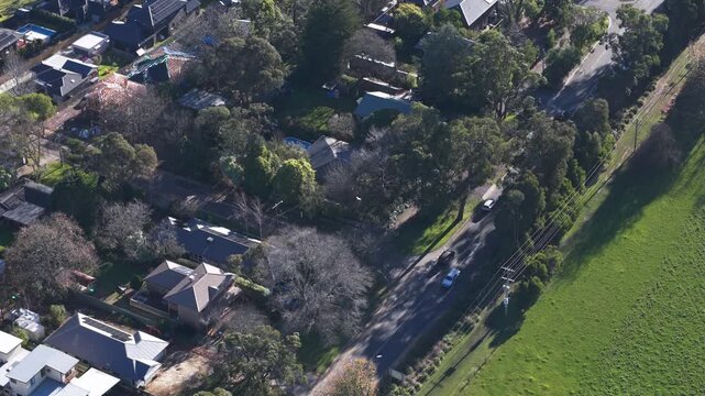 Drone footage captures tree-lined streets, modern suburban houses, and open green fields in South East Melbourne. Bright daylight, clear skies, and a peaceful residential atmosphere.