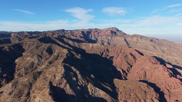 Folded sedimentary mountains of the Andes Precordillera rise above National Route 150, Calingasta, San Juan, Argentina, revealing deeply incised canyons and arid terrain, drone forward flyover