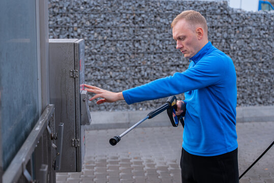 Man Washing Car at Self Service touchless Car Wash Using cashless payment terminal and professional washing equipment. The process includes paying through digital machine. Cardpayment and contactless