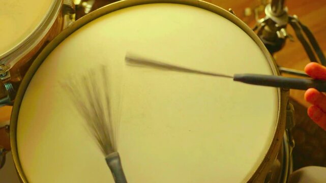 Drummer playing snare drum with wire brushes in a top down studio view