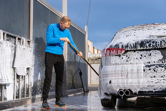 Concept of vehicle maintenance, car care, cleanliness transportation and modern automated washing services. Man Washing Car at Self Service Car Wash Using Foam Cleaning System