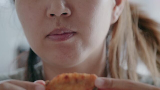 Close up of Asian woman holding and eating crispy fried chicken wing.