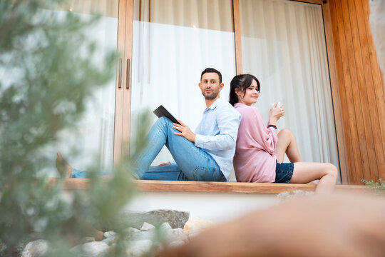 Couple relaxing on a terrace at home, using a tablet and enjoying a peaceful moment together. Concept of wellness, balanced lifestyle, remote living, and modern home comfort