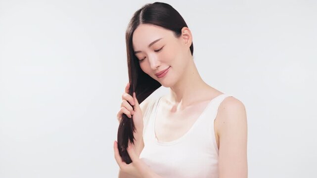 ヘアケアをするアジア人女性（ビューティー・コスメ・健康・澄んだ肌）