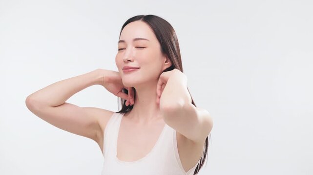 両手で美しい黒髪を後ろにかき上げる日本人女性（ヘアケア・美容・ツヤ・動作）