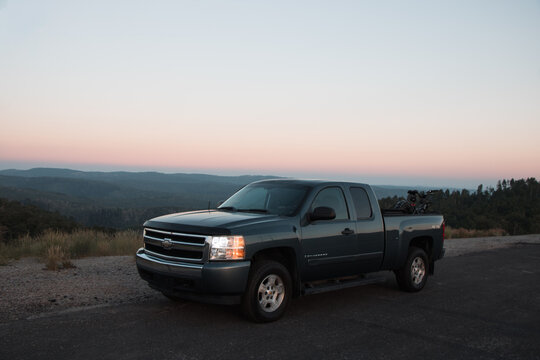 Pickup Truck with Mountain Bikes Parked at Monte Cristo Overlook Above Forested Hills Under Pink Smoky Twilight Sky, Highway 39, Northern Utah