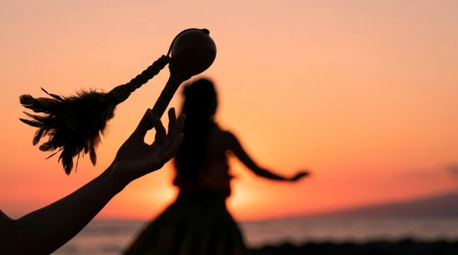 Silhouette of a hula dancer and uli uli instrument at sunset on a beach.