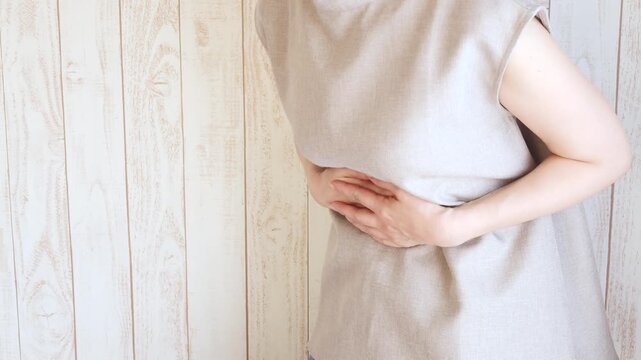 腹部の痛み前かがみになって苦しむ女性