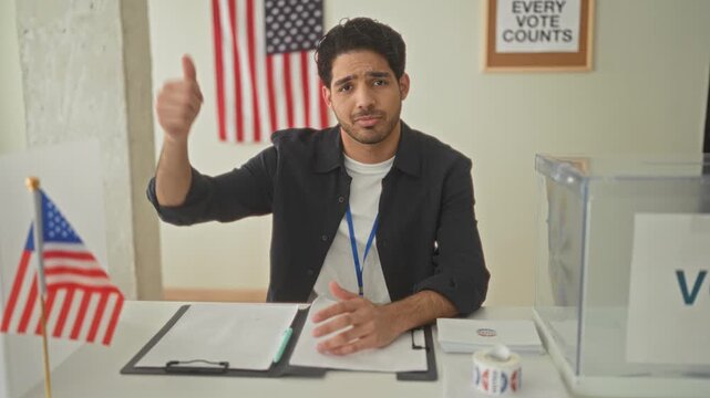 Man at a polling table giving thumbs down beside a clear ballot box, clipboard and us flag poster on wall in building; disapproval civic concern.