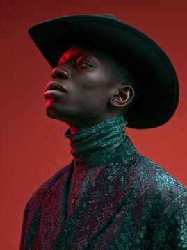 Stylish man in a black hat and patterned jacket with dramatic lighting