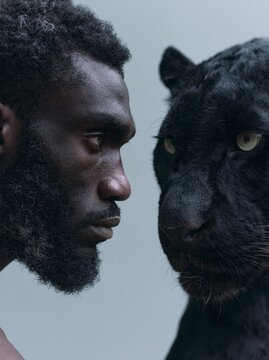 Close-up profile of a man and a black panther facing each other