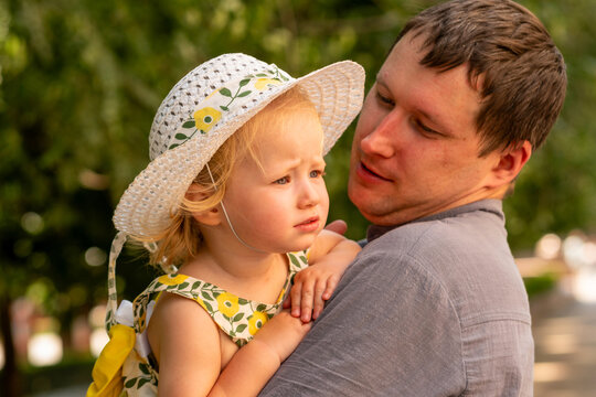 Father Holding Toddler Daughter During Sunny Park Walk