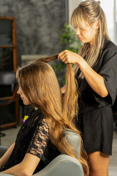 Hairstylist Separating Hair Of Teen Client In Beauty Salon