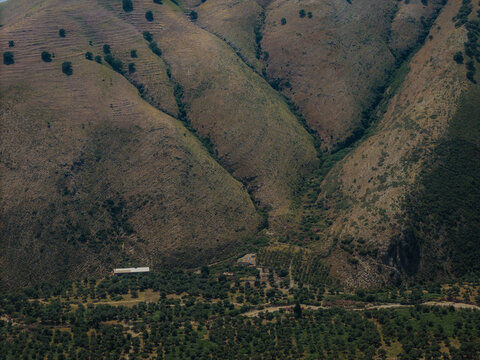 Aerial view of the rugged hills and olive groves surrounding the small village of Qeparo Fshat, Vlore County, Albania.