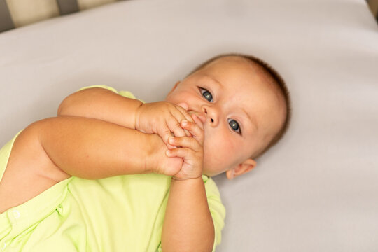 Curious Baby Son Holding Toes Near Mouth Indoors