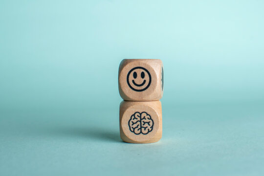 Wooden blocks symbolizing happiness and mental wellbeing with a smiling face and brain icon