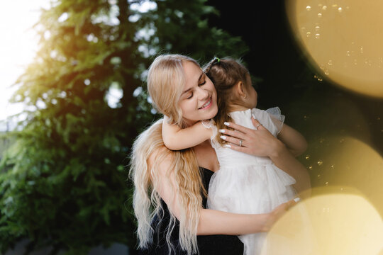 Heartwarming new year celebration with mother and daughter embracing joy, sunlight and bokeh light