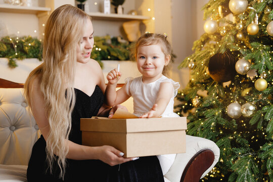 Mother and daughter writes letter about gift to Santa on eve of Happy New Year celebrating, on background christmas tree