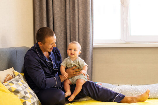 Father And Baby Son Smiling Together On Yellow Bed