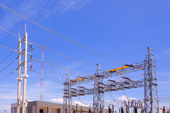 High voltage electrical power station equipment with transmission lines structure against blue sky background.