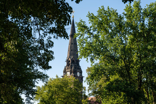 Garnison Church St Martin Dresden steeple framed by vibrant green trees under a clear blue sky on a sunny day. Historic architecture landmark in Saxony, Germany.