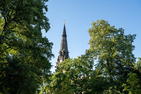 Garrison Church St. Martin in Dresden framed by lush green trees under a bright blue sky. Architectural heritage and urban nature combination in a scenic daylight view.