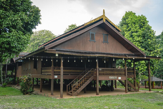 Traditional Souraja house of the Kaili people with a raised wooden structure, carved details, broad roof, stairs, and surrounding garden at TMII.