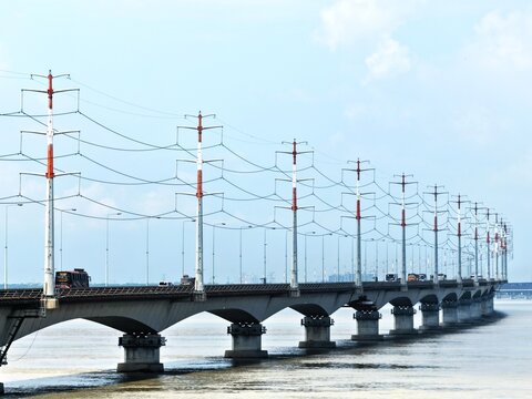 Aerial view of Jamuna Bridge spanning the river with power transmission towers and vehicles crossing the structure in Tangail District, Dhaka Division, Bangladesh.
