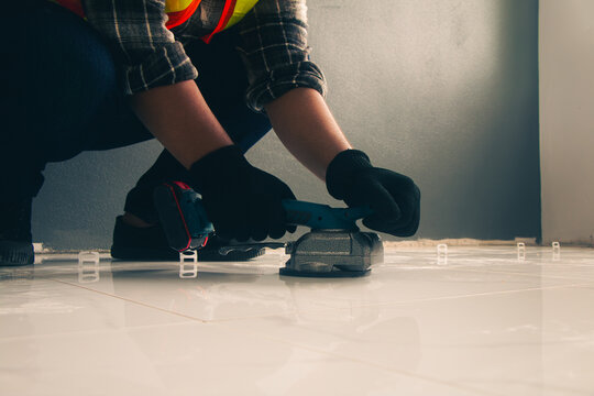 Technician laying tiles using a tile vibrator.
