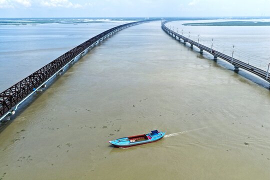 Aerial view of Jamuna Bridge spanning the wide Jamuna River with a cargo boat navigating the water in Tangail District, Dhaka Division, Bangladesh.