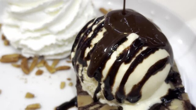 Close-up of creamy vanilla ice cream topped with rich chocolate sauce, creating an indulgent dessert with elegant presentation.