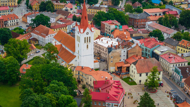 Aerial view of St. John's Church surrounded by historic red-roofed buildings and lush green trees in Cesis, Cesis Municipality, Latvia.