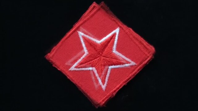 Red embroidered military star patch rotating slowly on black background