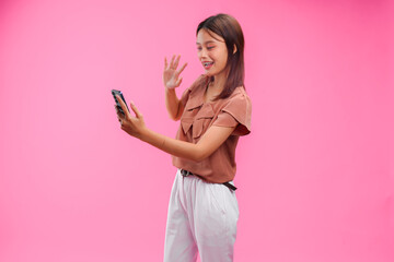 Smiling young Asian woman is holding a smartphone and doing video call pose. © ChristyMerry