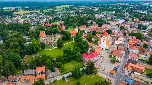 Aerial view of the historic Cesis Castle ruins and the landmark St. John's Church surrounded by lush green trees and red-roofed buildings in the town of Cesis, Cesis Municipality, Latvia.