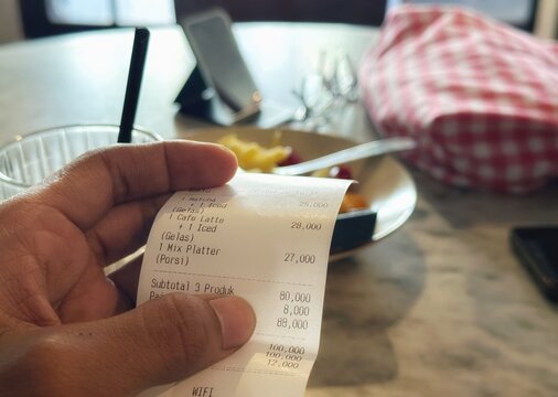 Hand Holding Cafe Payment Receipt Showing Order Items and Bill Amount
