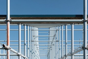 Naklejka premium Scaffolding tubes and couplers seen from below, featuring galvanized steel and mortar-spattered boards for construction and industrial marketing