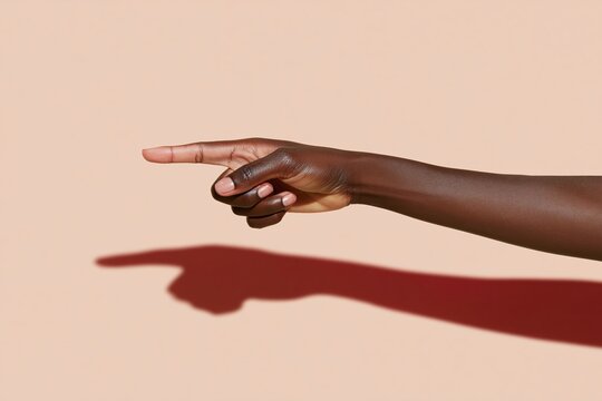 Dark skinned hand pointing with index finger, featuring smooth skin texture and a soft glow against an amber background for accusation and direction concepts, with copy space