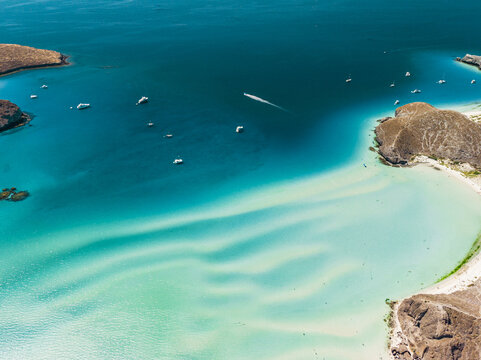 Aerial view of Balandra Beach with shallow turquoise waters, white sandbars, and rocky hills, La Paz, Baja California Sur, Mexico.