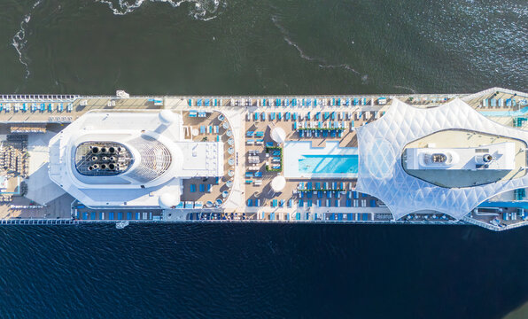 Aerial view of a large cruise ship deck featuring swimming pools, rows of lounge chairs, and modern ship structures in Stockholm, Stockholm County, Sweden.
