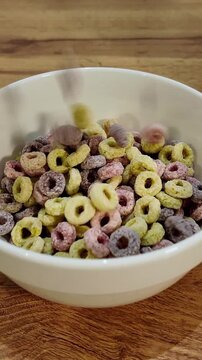 Pouring colorful breakfast cereal loops into bowl